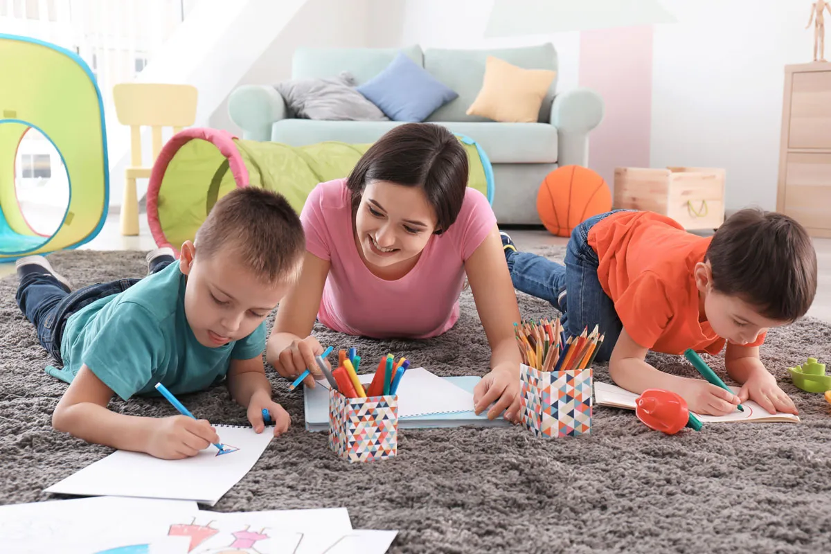 Babysitter with two children colouring